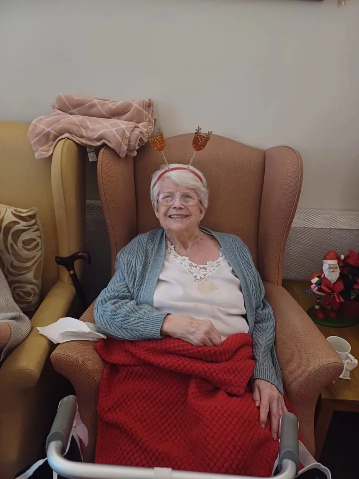 A smiling woman shows off her Christmas hat