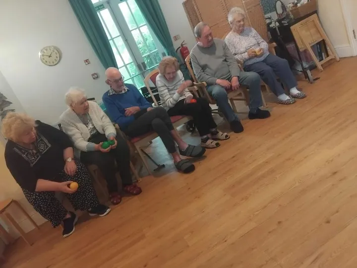Several people sit in a line together playing boule