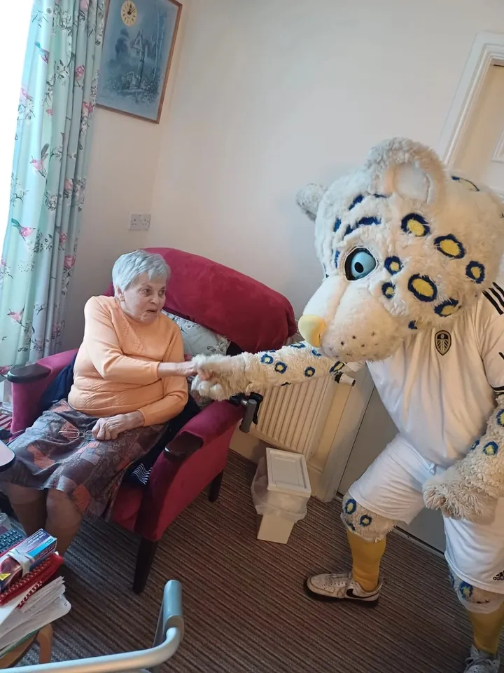 The Leeds United mascot bumps his fist with a woman