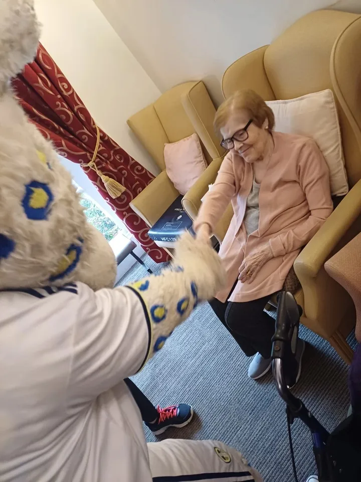 A smiling woman is greeted by the mascot