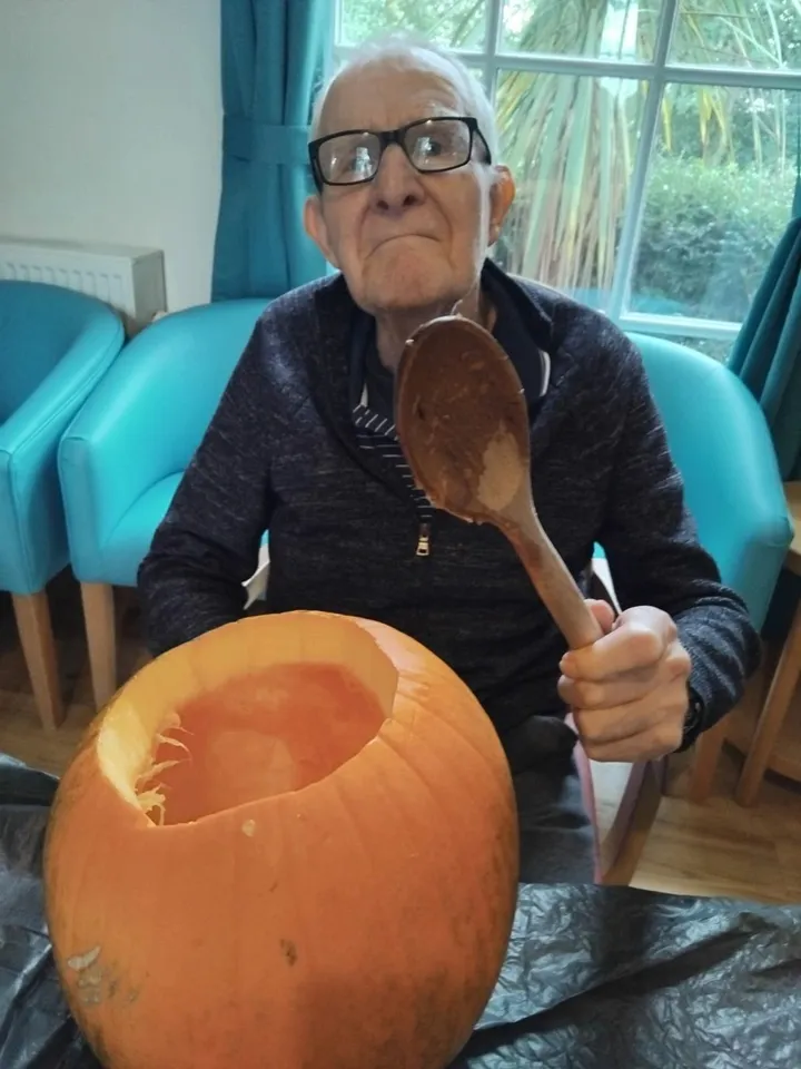 A man proudly brandishes his wooden spoon at his pumpkin creation