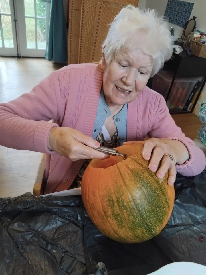 A woman gets to work carving out the inside of a pumpkin